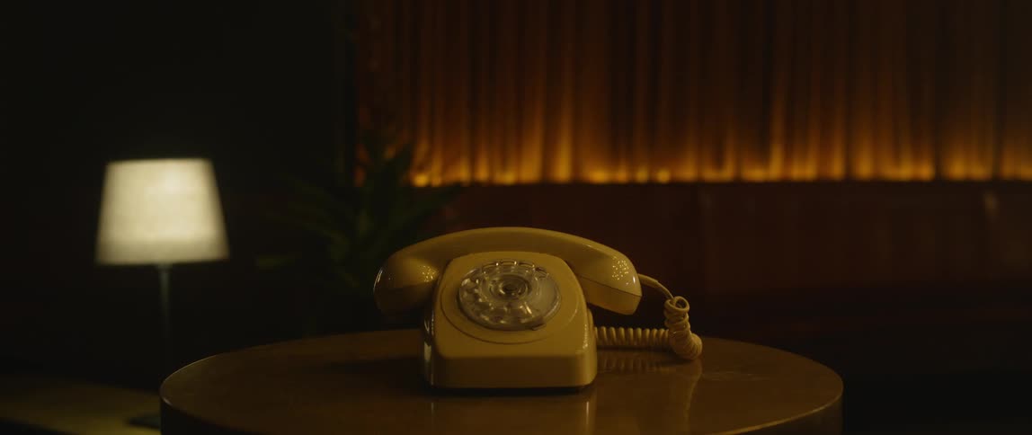 The yellow phone sits on the table in the dark room