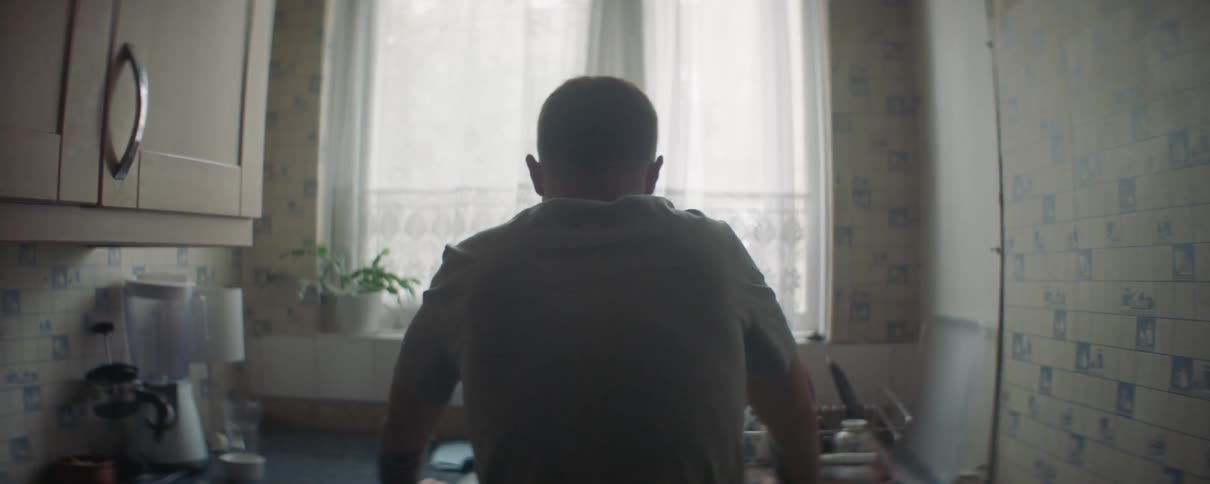 A man leans over the sink in the kitchen