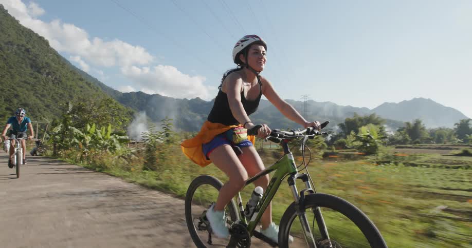 People ride their bicycles down the path on a sunny day