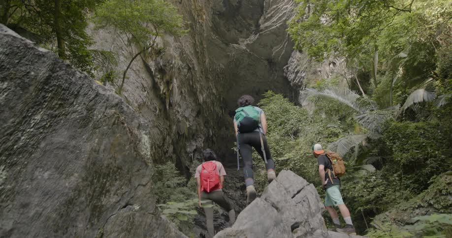 Three people rock climbing look up at a tall rock formation
