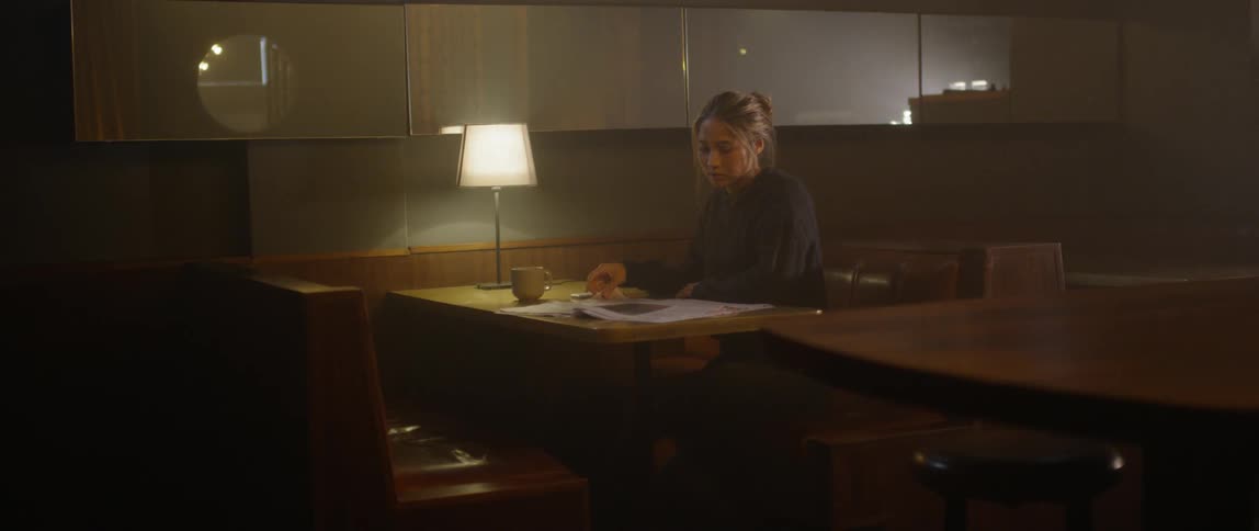 A woman sits alone in a restaurant booth