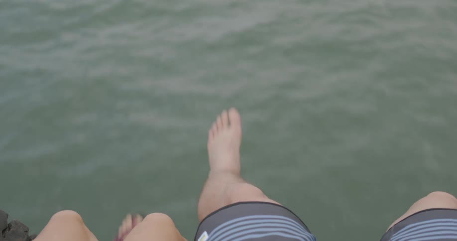 Two people dangle their legs on a moving boat