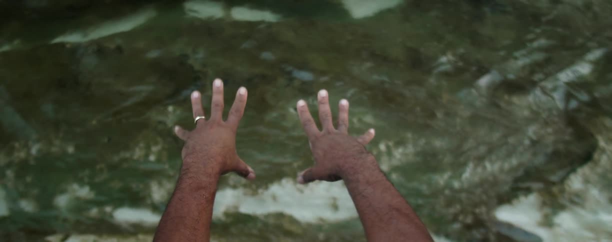 A man stretches his wrists above the flowing water