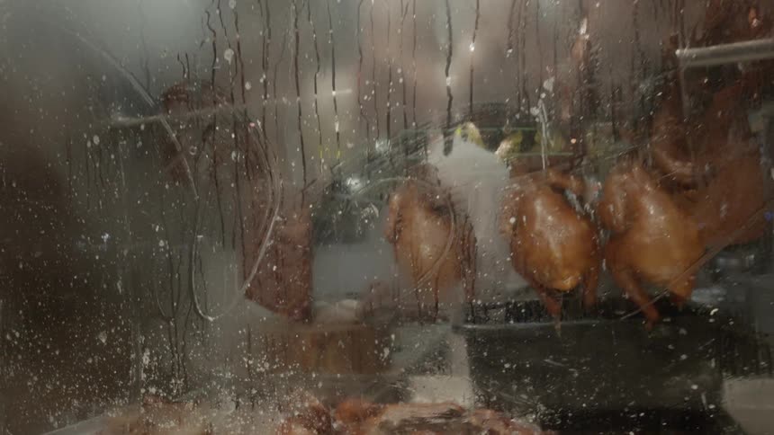Water streaked windows show trays of food behind them