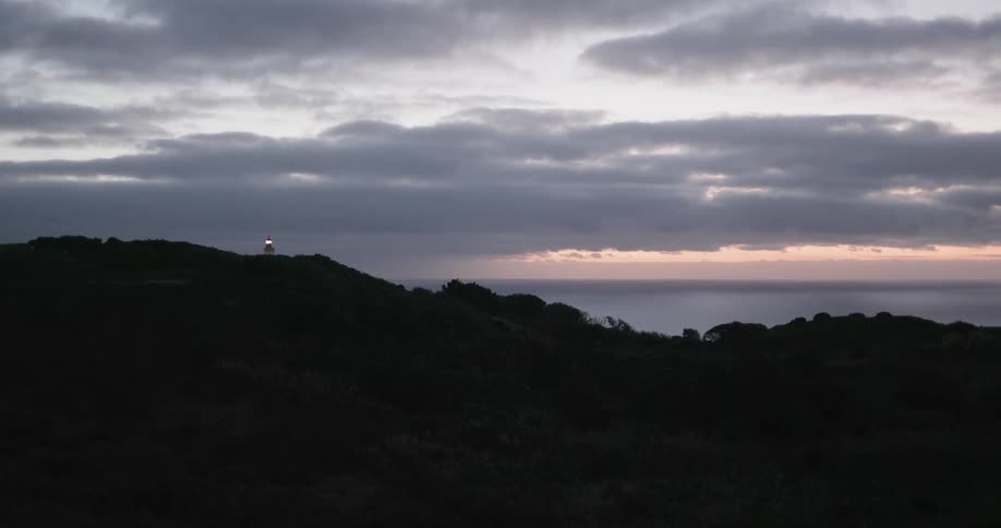 A lighthouse flashes at sunset
