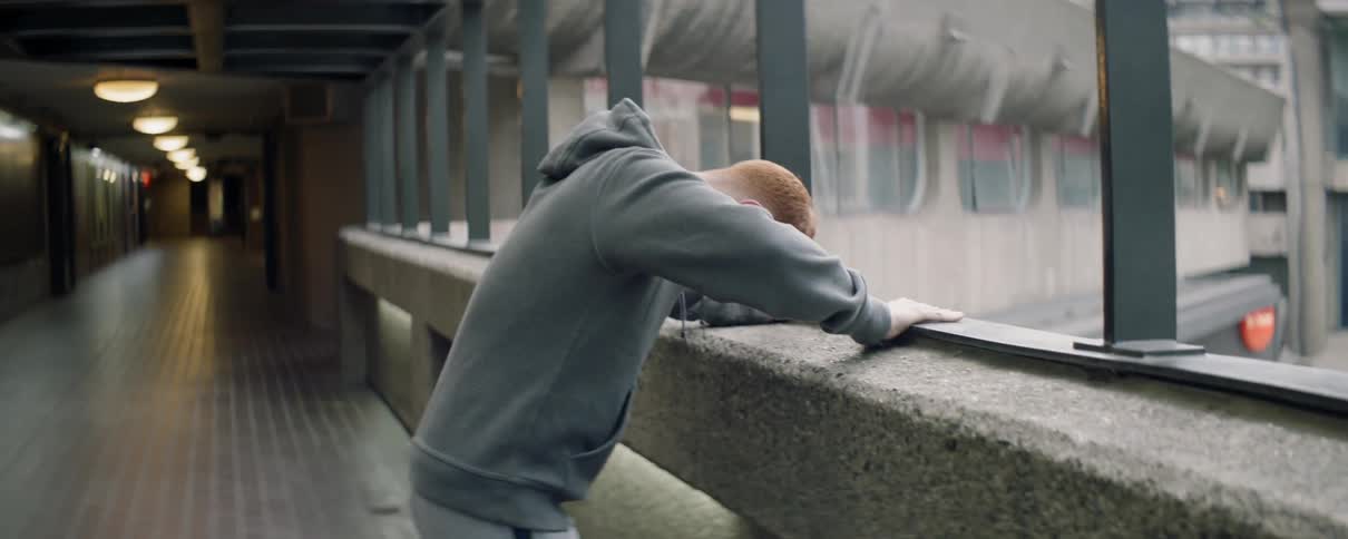 A man leans against the railing before checking his watch