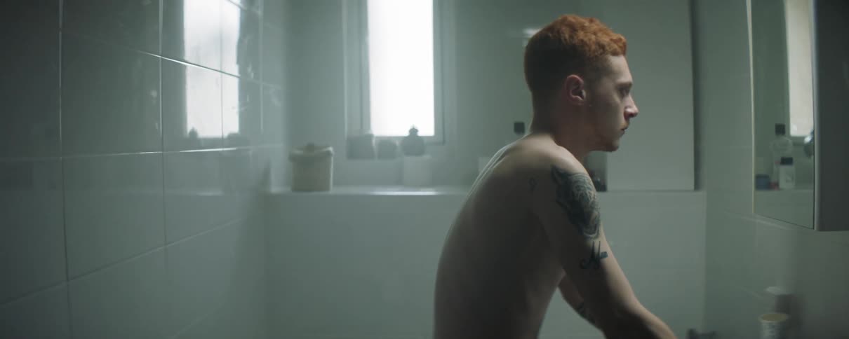 A redheaded man stands in a bathroom