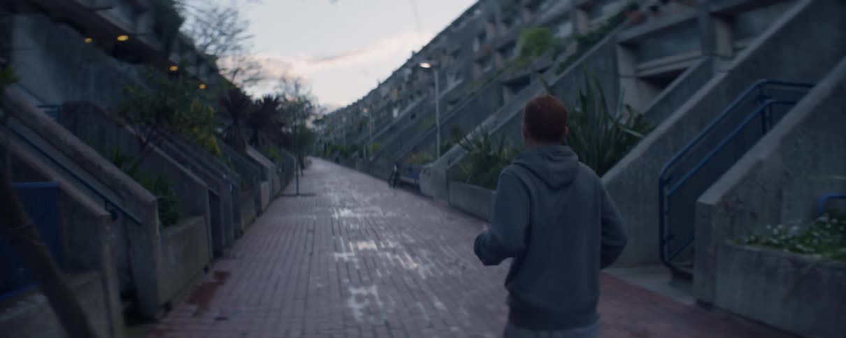 The man is jogging past the apartment complex