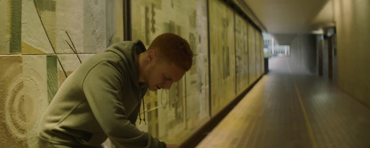 Man breathes heavily while leaning against a wall