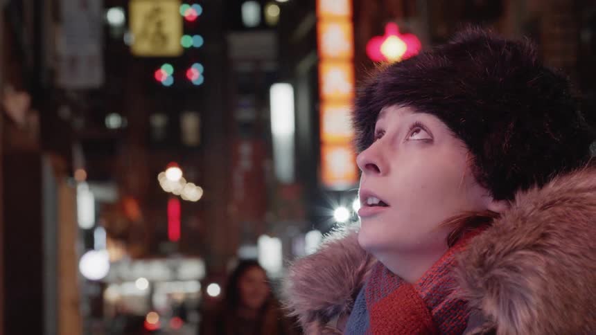 Woman stands on a city sidewalk in a heavy coat