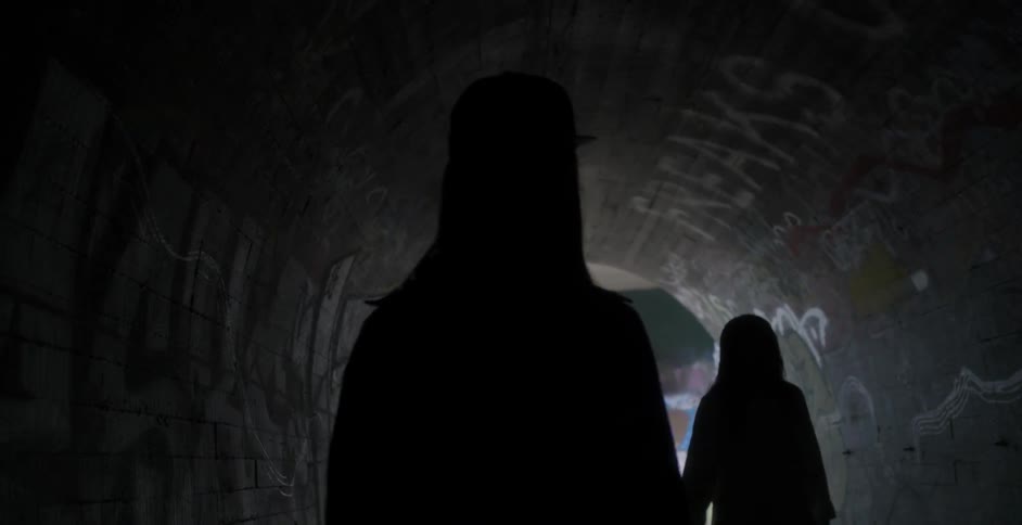 Two women walk in a dark tunnel
