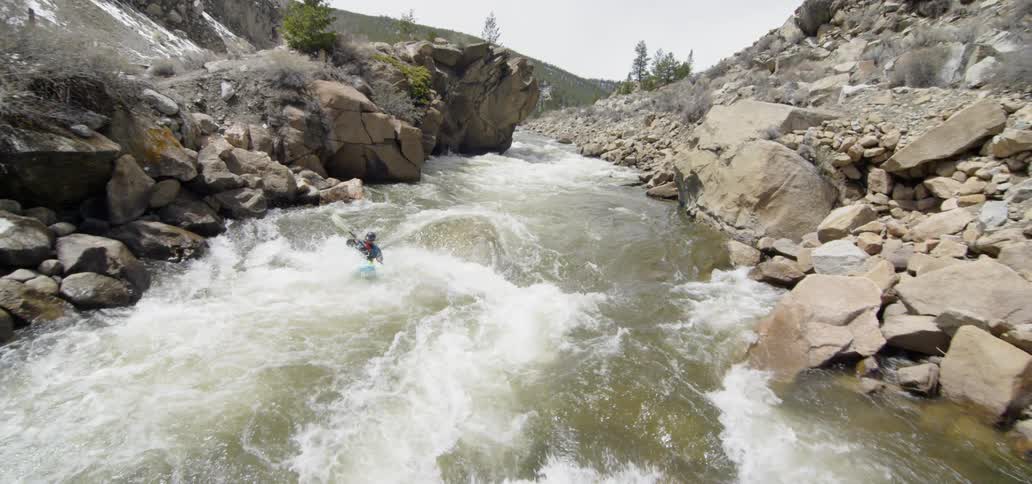 Man kayaks over river rapids