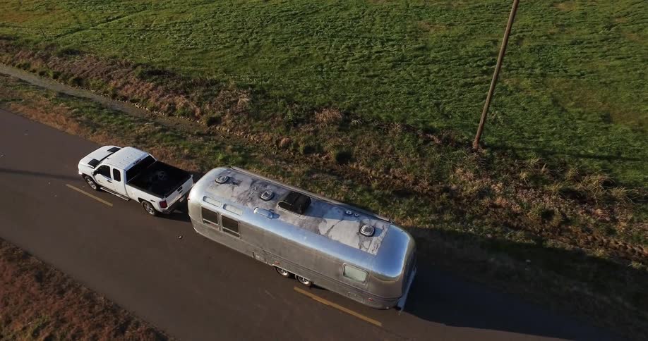 Truck pulls a silver trailer through the country