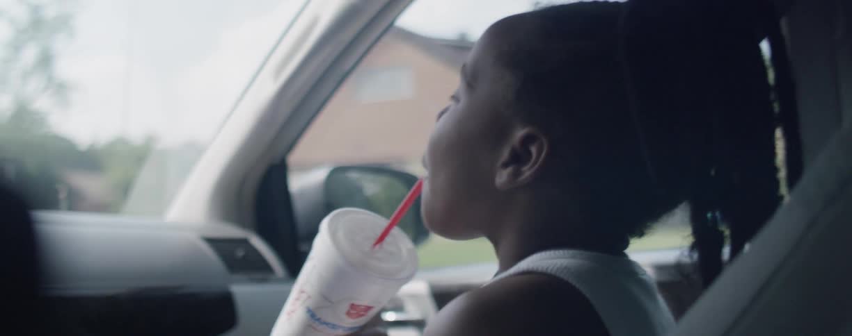 Girl sips on a drink while riding in a car