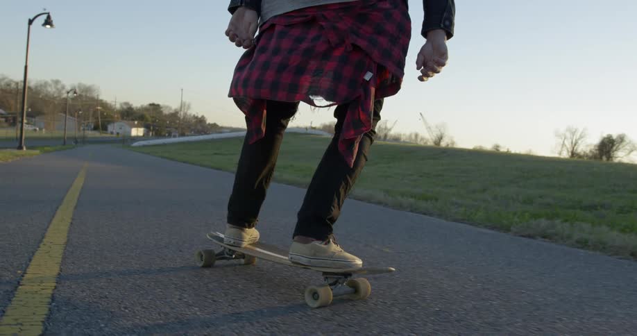 Person is riding skateboard down street in the evening