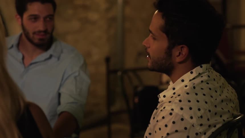 A man talks with friends sitting outside