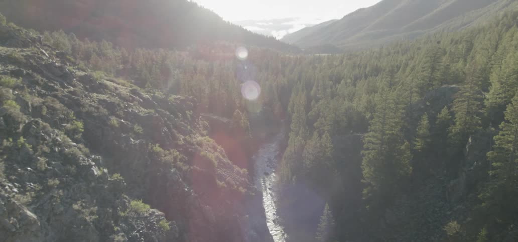 The sun shines on the valley between mountains