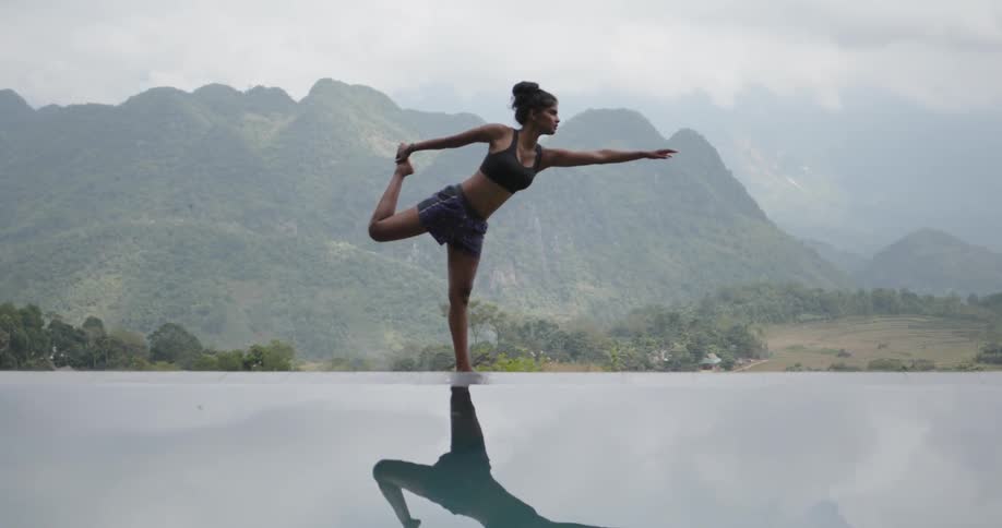 Woman practices yoga near a calm lake