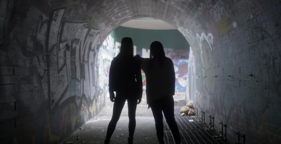 Two women stand inside a tunnel