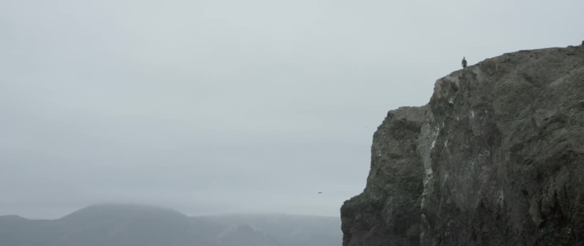 Man standing near edge of a high cliff