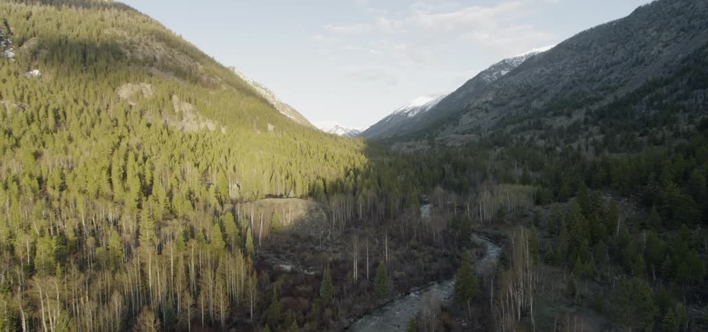 The sun shines on a valley between mountains