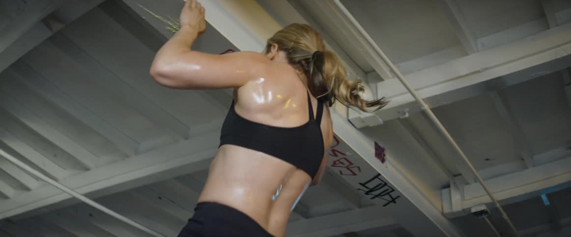 Woman does chin ups on the ceiling of a warehouse