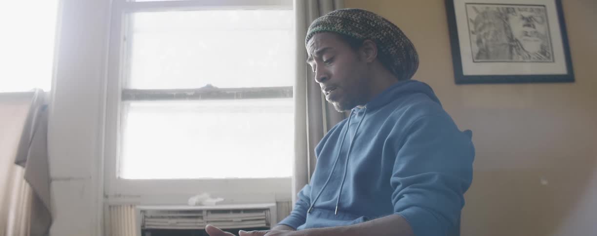 A man sits down singing by the window