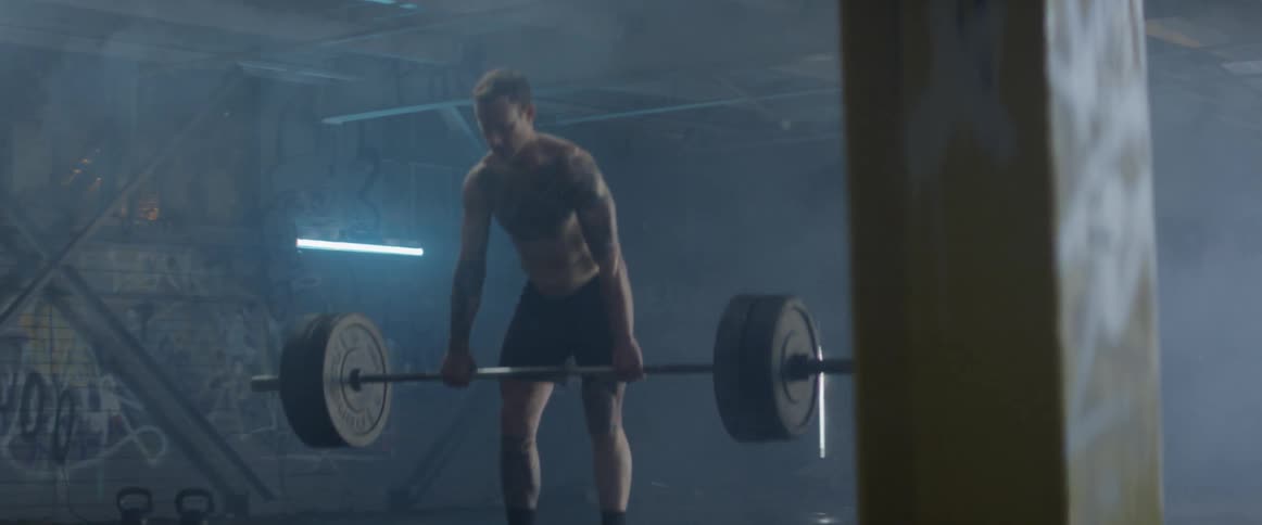 A man is lifting a heavy barbell in the gym