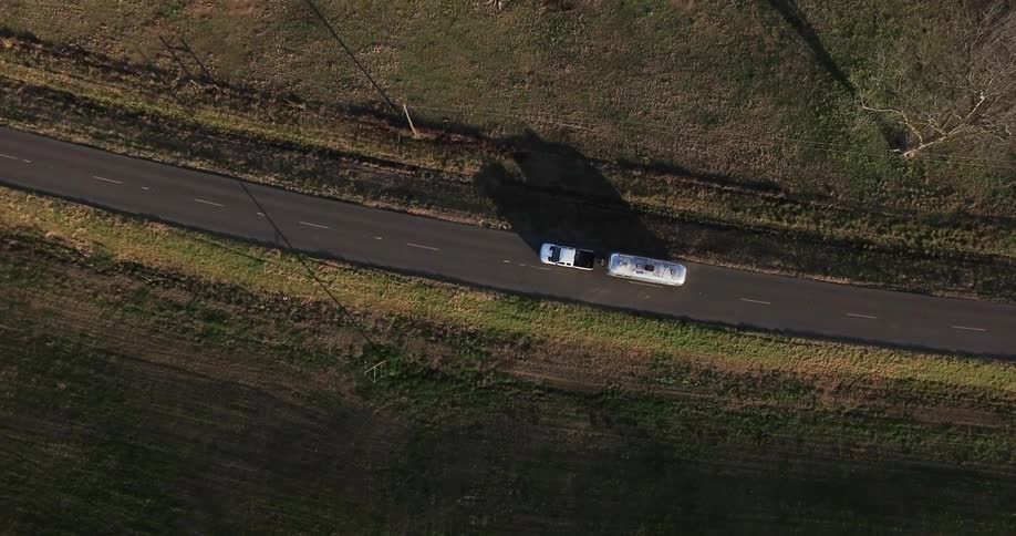 The truck is pulling the trailer down the road
