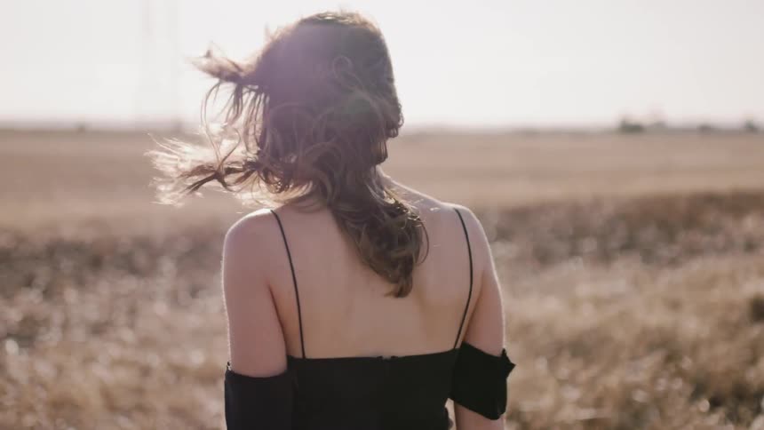 Woman walks in a rural field on a windy day