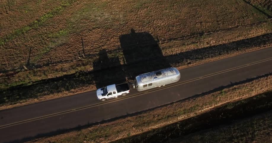 Truck drives down a country road pulling a silver trailer