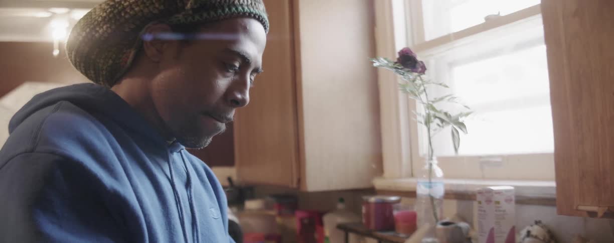 A man is cutting an avocado inside his kitchen in daylight