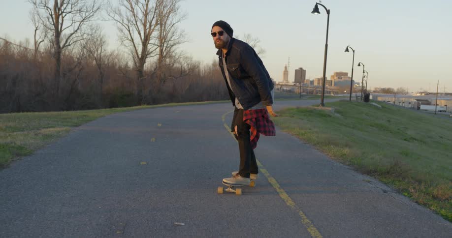 Man is skateboarding down a path outside city
