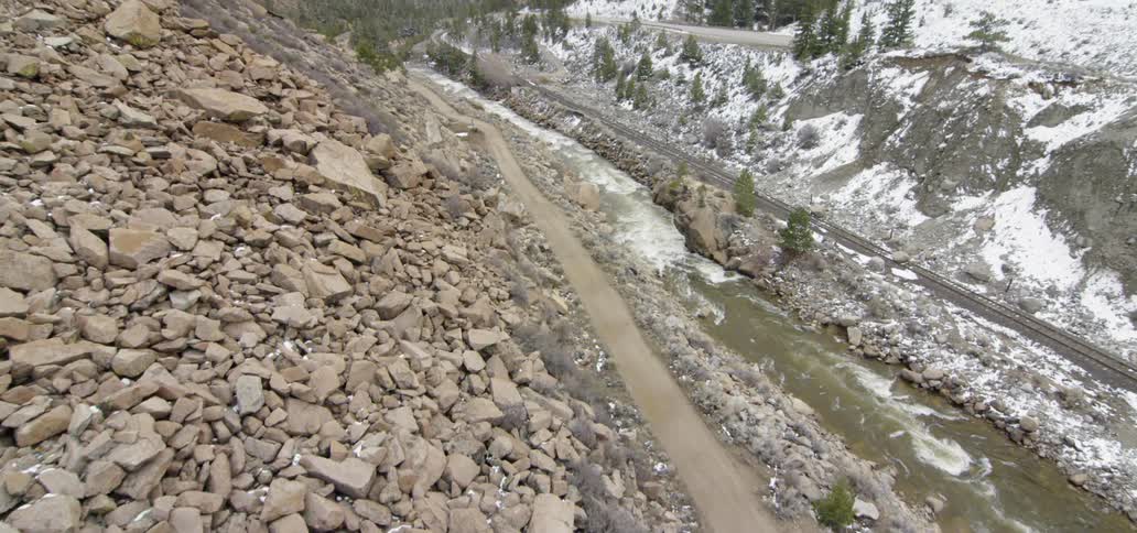 A river runs rapidly at the foot of the hills