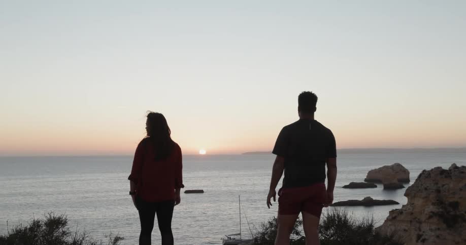 Man and woman look out at the lake as the sun sets