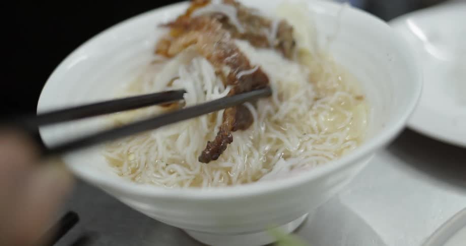 Person eats soup with chopsticks