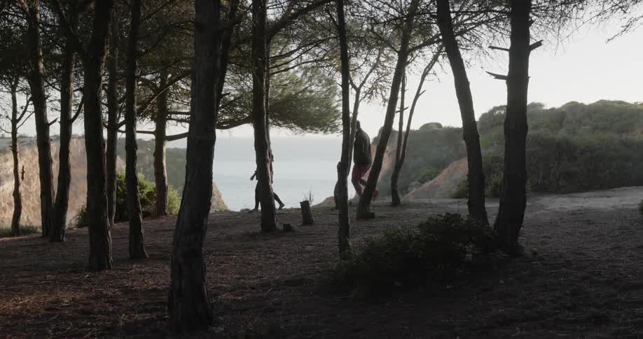 A man and woman walk past trees on a ridge