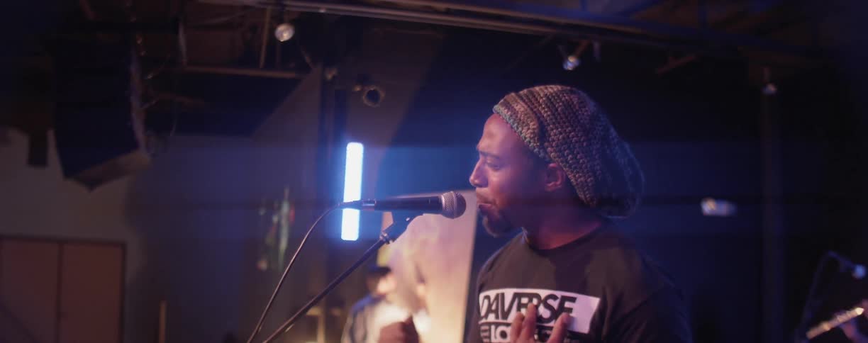 Man sings into a microphone on stage