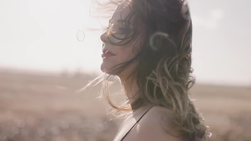 Woman stands in a rural field on a windy day