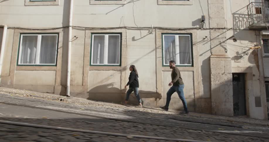 Man and woman walk up a hill next to a building