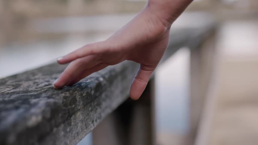Woman is gliding her fingers along a wooden railing