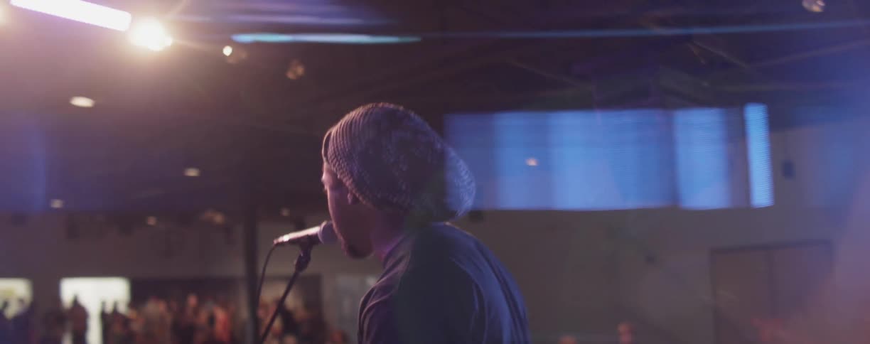 A man is singing into the microphone for a crowd