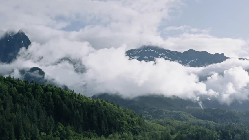 Clouds float around a mountain - 4K Aerial