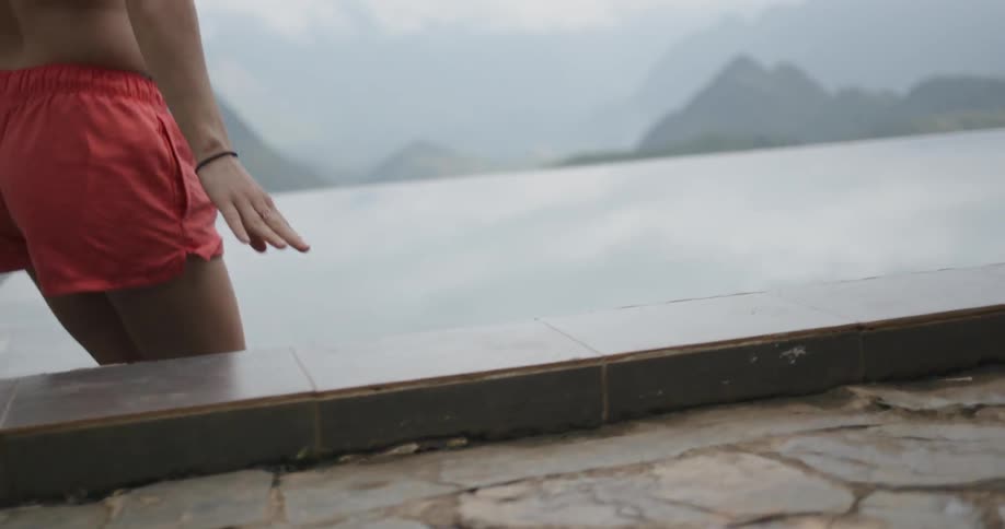 Woman climbs into a swimming pool in the mountains