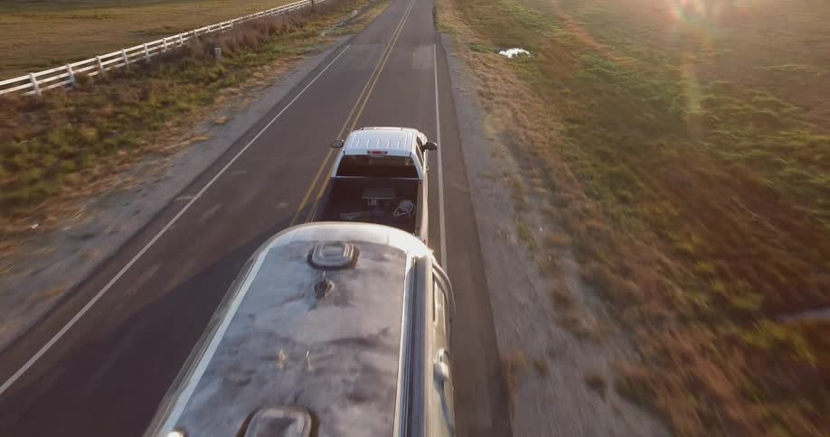A truck pulls a trailer on a rural road