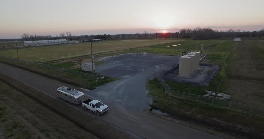 Truck pulling travel trailer is driving on country highway at sunset