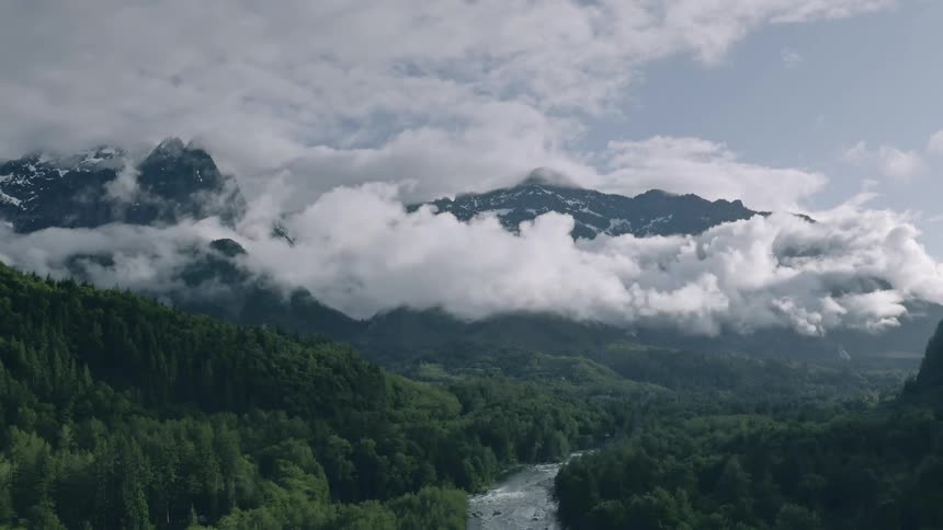 Clouds pass near the tall mountains - 4K Aerial