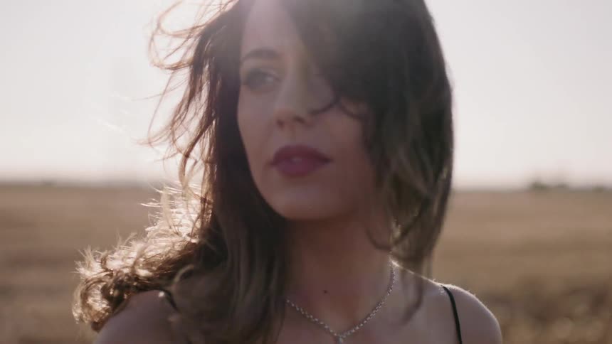 Woman stands in a field and looks towards the distance