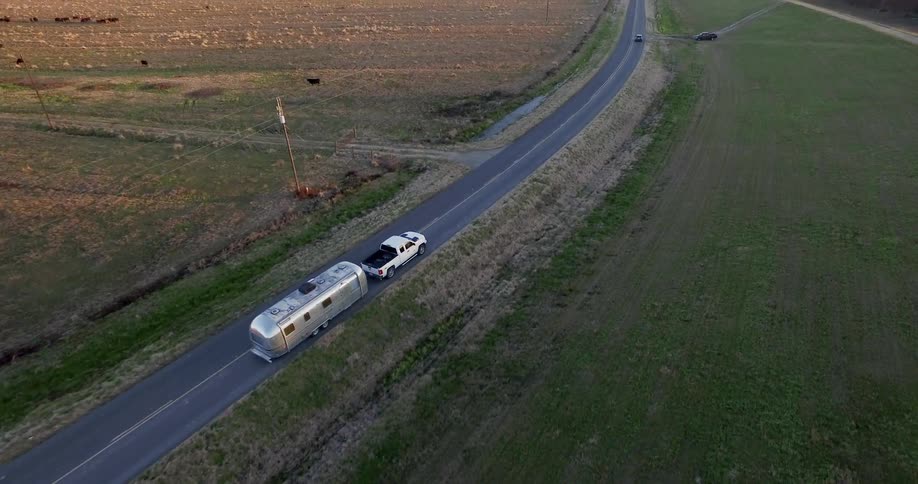 Truck pulling travel trailer is driving on country highway