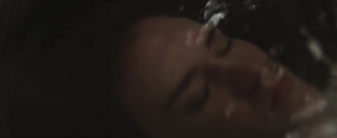 A person closes their eyes as they submerge into the bath water